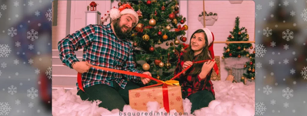 A couple sitting in front of a decorated Christmas tree unwrapping a gift in a snowy, Hallmark-style holiday setting.